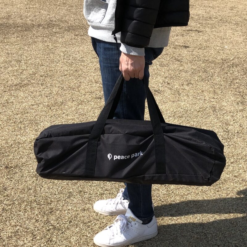 ピースパークフォールディングウッドテーブルを収納袋に入れて運ぶ画像